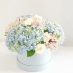 Gift your loved one a beautiful arrangement of white roses and blue hydrangeas in a round light blue box