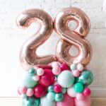 This arrangement features two giant number balloons (not helium) and latex balloons. The balloon color theme and numbers can be customized to your preference. Giant numbers are available in gold, silver, and rose gold, and they are 32” in size.