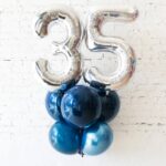 This arrangement includes one giant number balloon and five helium latex balloons. The color theme and number can be customized to your preference.