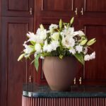 Surprise your loved one with an exquisite flower arrangement featuring pristine white roses, elegant white chrysanthemums, and delicate white lilies, all beautifully presented in a classic brown pot. A timeless gift that radiates pure elegance and charm