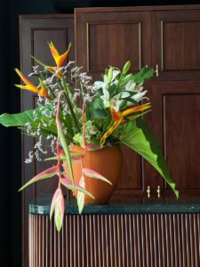 Surprise your loved one with an exquisite flower arrangement featuring vibrant heliconias, alluring Sexy Pink heliconias, delicate lilies, and lush hydrangeas, all elegantly presented in a stunning orange pot. A gift of beauty and grace that speaks volumes