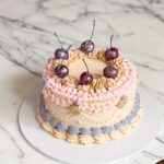Gift your loved one a ribbon cake topped with maraschino cherries and edible glitter! The cake measures 6 inches in diameter and 4–5 inches in height, making it a perfect treat for any special occasion.